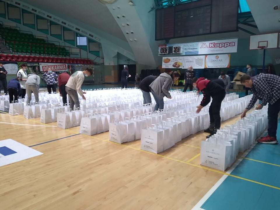 Grafika przedstawia wolontariuszy z SP 4, którzy pomagali przy pakowaniu potraw wigilijnych dla potrzebujących