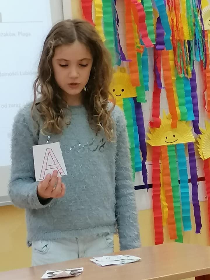 uczennica prezentuje kartkę z literą A