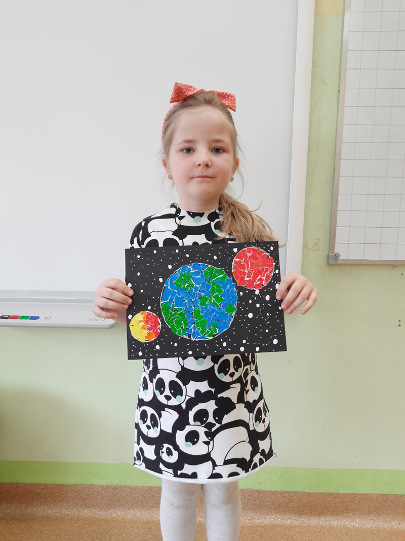 Grafika przedstawia dziewczynkę z koła plastycznego prezentującą  prace wykonaną z okazji Dnia Ziemi