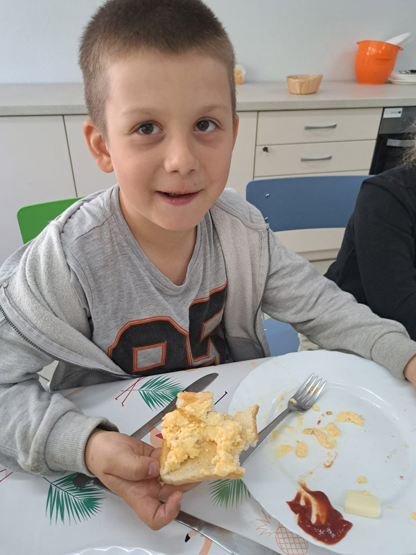 Grafika przedstawia chłopca z klasy 1c jedzącego jajeczniczke z chlebkiem